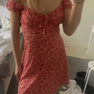 Klänning  - Röd och vit blommig klänning, aldrig använd 