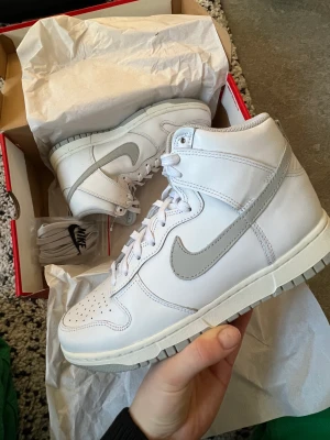 Helt nya vita dunk high - Helt nya höga dunks med gråa detaljer. Kommer med vita och gråa snören. Storlek 39 Kan tänka mig att byta också:)