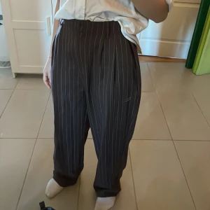 Bruna, randiga kostymbyxor - De här kostymbyxorna är 36or från grunden, men insydda till storlek 34. Stilen är ganska casual, men elegant. Jag har haft dem i ett halvår cirka, men endast använt dem en gång så de är i gott skick.