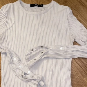 Ribbad långärmad tröja  - Ribbad tight långarmad tröja ifrån bikbok med knapp detaljer på armarna. Passar xs-s