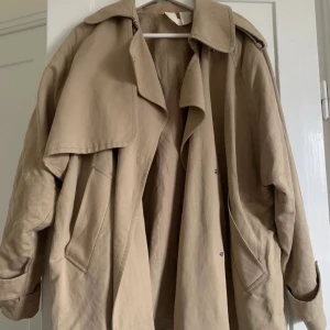 ARKET trenchcoat  - Säljer min fina trenchcoat korta modellen från ARKET. Kommer tyvärr inte till användning. Jag är 160cm lång för referens. Knappen på bild på ena axeln går ej att stänga men kan enkelt fixas. 