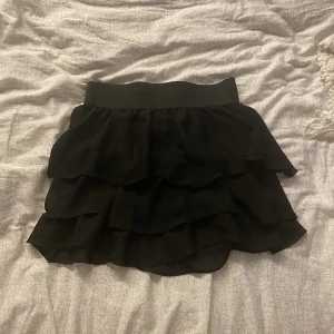 Svart volangkjol - Säljer suuperfin svart volangkjol då den tyvärr är för stor för mig💕 storlek L, Ifrån Vero Moda och har stretchigt resårband💖fint skick 