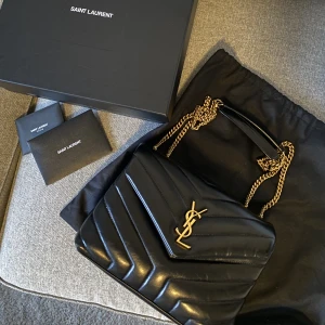 YSL lou lou bag - Säljer min YSL LouLou bag small i svart/guld. Köpt på NK 2021. Kvitto, äkthetsbevis och det på bilden medföljer. Sparsamt använd och i fint skick. Små defekter ses på bild 3 (båda sidor). Mer bilder finns. Nypris ca 28.000. INGA PRISFÖRHANDLINGAR/BYTEN