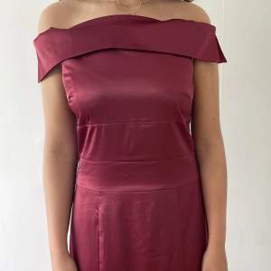 Lång mörkröd silkesklänning som har en offshoulder stil vid axlarna.   Klänningen är använd enbart 1 gång och säljs pga platsbrist. 