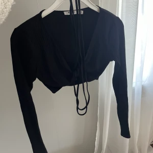 Festtopp NA-KD  - Svart festtopp från NA-KD med långa ärmar och snören som man knyter runt midjan🌸använd fåtal gånger ☺️