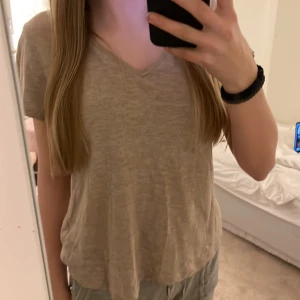 V-ringad T-Shirt  - Storlek: S  V-ringad T-Shirt som är beige. 