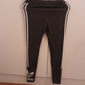 Tajta adidas byxor - Tajta mörkgråa adidas byxor, använda nångra gånger har ganska okej skick, färgen på adidas märket längst ner börjar försvinna lite men de e inget man tänker på och så e de en nagelacks fläck nånstans men syns inte