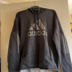 Adidas hoodie  - Grå och mörkgrå detaljer, fickor där fram. Bra skick. Storlek L, märke Adidas. 