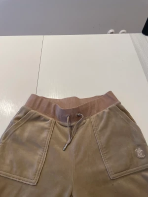 Juicy couture velour byxor  - Beigea/ warm tapue velour byxor från Juicy couture. Storlek Xs, nästan aldrig använda, kan ha ett litet märke på benet där fram ( syns inte alls mycket). Säljer pågrund av att de är för stora. 