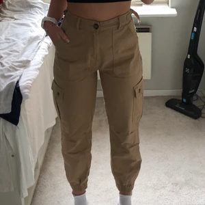 Pull&Bear cargopants strl 34 - Beigea/ljusbruna cargopants från Pull and Bear. Resår i benens nederkant och justera band i midjan, strl 34 men passar även 36 så lite stora i storleken. Försmå för mig därför säljer jag men annars sköna och bra byxor. Hör av er vid frågor eller om du vill se fler bilder!