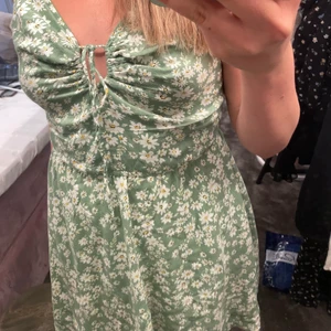 Grön blommig klänning💚🌼 - Grön blommig klänning från Bikbok. Knytning fram, smala band, ungefär ovanför knänen. 🍀