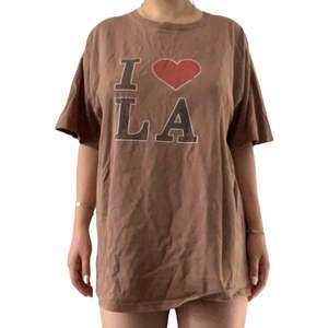 Brun T-shirt med texten I ❤️ LA. Sliten och har ett hål men är fortfarande väldigt bekväm. 