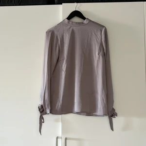 Silver satintopp - Silvrig satintopp med knytning vid handlederna och i nacken. Nyskick