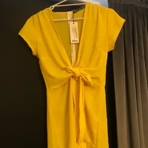 En gul super fin somrig byxdress från boohoo. Knytband i midjan och v ringad fram med dragkedja baktill. Finns i Nässjö 