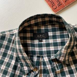 Ca. 2010 forest green tartan shirt with folded sleeves held up with a buttoned strap. Mens size S but fits like XS. Sparingly used, but there is an 8mm tear by the 3rd button from the top. Not visible and easily fixed.