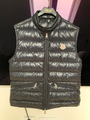 Moncler gui väst - Hej säljer nu min fina moncler väst i väldigt fint skick skulle säga 8/10! Färg navy blue. Nypris:-6990kr Storlek:- 1/S-M Priset är inte hugget i sten kom med bud!