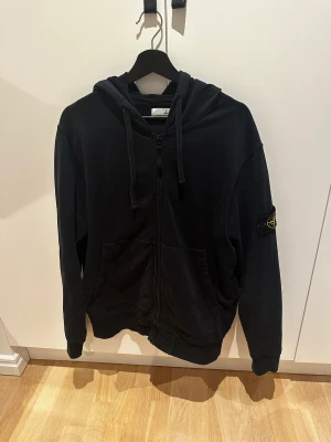Stone Island Zip Hoodie - Tja, säljer min stone island hoodie då den inte kommer till användning längre. Den är i bra skick och köpt för 3000kr på farfetch. Den är i storlek XL men passar L. Den är mörkblå men nästan svart