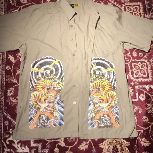 Skjorta m tigrar - Kortärmad skjorta med tigrar, stenade ögon. Bra skick, typ aldrig använd. 