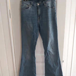 Utsvängda jeans från Crocker - Utsvängda, mellanblå jeans i stretchigt material från Crocker. Detta var mina favoritjeans så tyvärr har dom en slitning under bälteshållarna (bild 3) men annars i fint skick