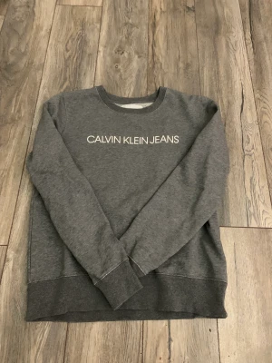 Calvin Klein Jeans Sweatshirt  - Väl använd tröja under ca 1 års period. Tröjan ser som ny ut men den är lite sträv på insidan. Den sitter fint och bra storlek. Tröjans nypris var 749 kronor, priset kan diskuteras! 