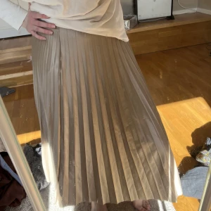 plisserad kjol - jätteelegant plisserad kjol i en champagneaktig färg! superfin nu i vår och sommar, sitter jätteskönt och smickrande då den har resår i midjan. köpt secondhand.