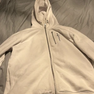 Sail racing hoodie - En vit sail racing hoodie som jag Hartvig över ett år. Den är i ganska bra skick men dragkedjan på den lilla fickan är av men har kvar den och den är jätte enkel att sätta på. Skick 7/10