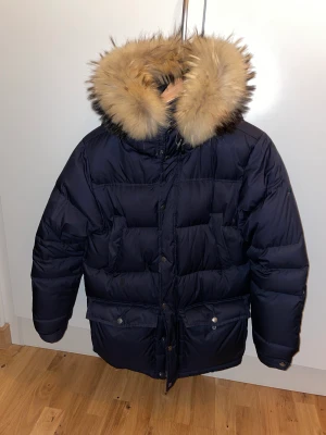Vinterjacka boomerang  - Vinterjacka från boomerang. Mörkblå. Går lite över rumpan. Står strl xs men de är stora i storlek och killen som haft den har ungefär M. Har lämnat in den hos skräddaren som syns på sista bilden men inte i verkligheten. Äkta päls. En av de varmaste vinter