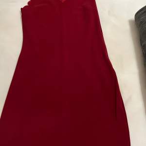 Vinröd klänning enligt ovanbilder som har en dragkedja på sidanom för att man får mer kurviga former.