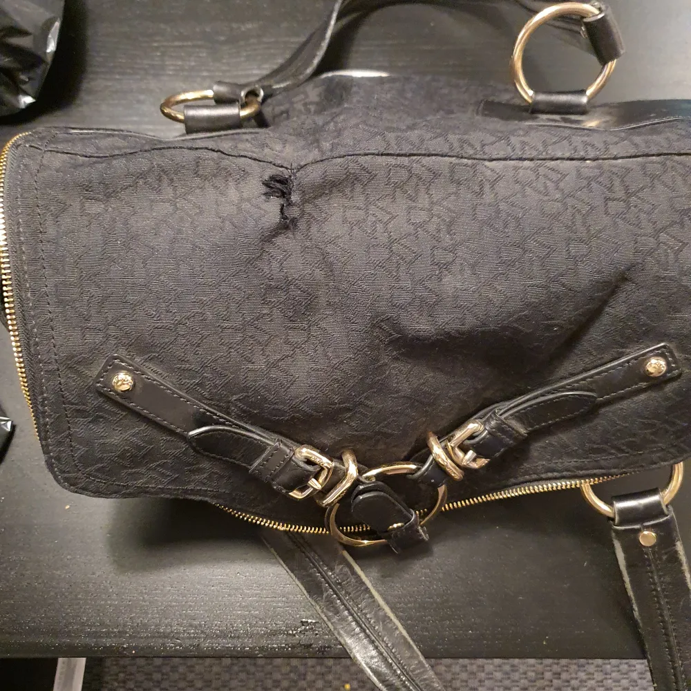 Väska från DKNY, äkta, välanvänd med lite slitage på handtag, se även bild med en skada på tyget.. Väskor.