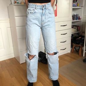 Ljusblåa jeans gina tricot - Storelk 34, bra i längden på en 168 cm person. Fina byxor med insperation från 90-talet med en hög midja och hål på knäna. 