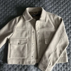 Beige kort kappa - Säljer denna fina korta kappa från zara då den inte används längre! Jätte fint skick och ser inprincip ny ut. Pris kan diskuteras vid snabb affär! Köparen står för frakten!