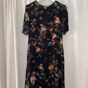 Klänning blommig - Strl L men kan justeras med ett bälte, en knapp fattas på ena axeln, inget man märker