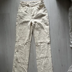 Jeans - Beige / vita utsvängda jeans från Bikbok i storlek 26. Knappt använda