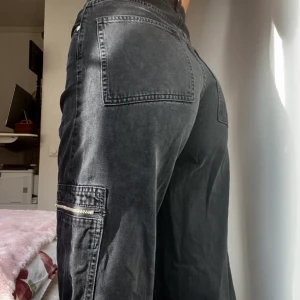 Cargo jeans - Svarta cargo jeans från weekday i en modell som inte längre säljs🐈‍⬛ passar någon som är upp till 170cm, annars går de inte hela vägen till fötterna💗 de är högmidjade (w25, l32) Går att knyta längst ned beroende på hur vida man vill att byxbenen ska vara🙏
