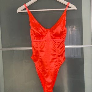 Neon orange body - Oanvänd body, endast testad! Den har blivit lite nopprig tvärr vid ryggen som man ser på tredje bilden pga den legat tillsammans med andra plagg i en påse. Detta syns inte alls men ändå viktig att nämna 