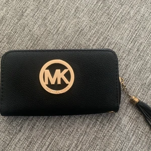 Svart Michael Kors plånbok - Michael Kors plånbok med många fack för kort samt ett med dragkedja. Skickas spårbart med Postnord