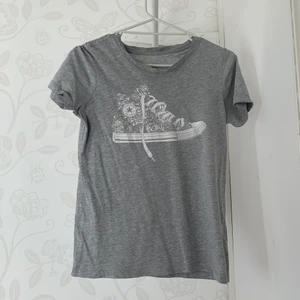 Converse T-Shirt Grå - Grå Converse tröja, storlek XS Tröjan är köpt i Kalifornien 2014 och är i samband med sin ålder välanvänd. Trycket på bröstet har inte flagnat , men själva plagget har tänjts ut lite i tvätten Den passar inte mig längre så en bild på hur den sitter på mig kändes fel. 
