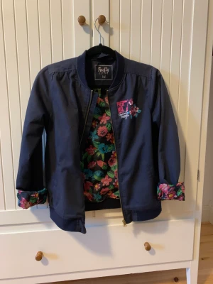 Jacka  - Marinblå jacka med blommig insida i storlek 160. 