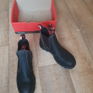 Redback kängor/skor strl 44 - Helt nya aldrig använda redback kängor. Nyinköpta för 1460kr för en vecka sedan.  Säljes pga har dubbla par. Riktigt sköna med stålhetta som knappt märks av.