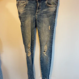 Zara Trafaluc jeans - Blå jeans med slitningar framtill från zara. Tajta och högmidjade.  Kunden står för frakt, inga byten.