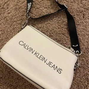 Calvin Klein  - Säljer denna jätte snygga Calvin Klein väskan med svart band. Använt fåtal gånger. Man kan även ta bort bandet på väskan. 