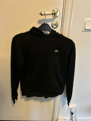 Lacoste hoodie svart - Storlek: 152 Nybart skick, används endast en gång. Köpte varan för 650kr säljer för endas 200kr pga ej varit till användning.