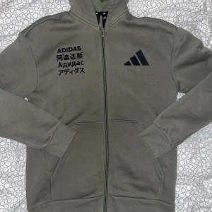 Grön ”Adidas” Hoodie - Grön Adidas Hoodie. Storlek 164-170 (14-15yr). Knappt använd, inga märken/hål/smuts och kvaliten är väldigt bra. Kunden betalar frakten 😚.