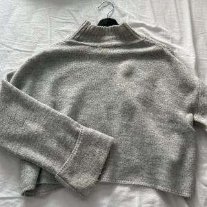Stickad tröja  - Grå stickad tröja med hög krage samt vikta ärmar. Lite croppad. (Om du vill se plagget på skriv privat)