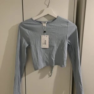 Ribbad tröja med öppen rygg - Hej säljer helt oanvänd topp från Monki, öppenrygg med knytning  Prislapp kvar 