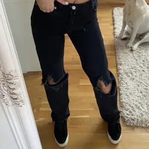 Svarta jeans med hål på knäna 