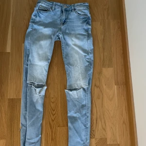 Jeans - Lågmidjade ljusblåa jens med hål i knäna.  Säljer pågrund sv att jag inte gillar att ha lågmidjat