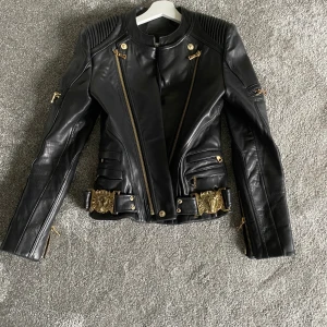Lyxig skinnjacka  - Svart custommade skinnjacka med guld detaljer, köpt från USA ca 5000kr, använd max 5 ggr passar 34/36