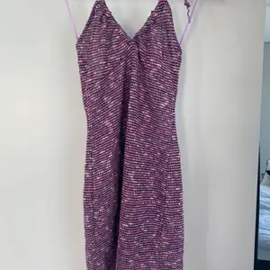Virkad lila/rosa/vit klänning med halterneck knytning från pull & bear. Aldrig använd, prislapp kvar. Storlek L men passar S/M