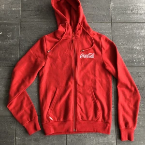 Coca cola Hoodie! - För dam är den uppskattad strl M.  Inköpt på Gröna Lund för 600 kr. Endast provad. 